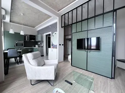 a living room with a chair and a sliding glass door at Broz Apartment in Belgrade