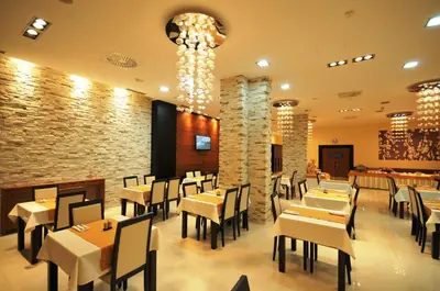 a restaurant with tables and chairs and a stone wall at Garni Hotel Nevski in Belgrade