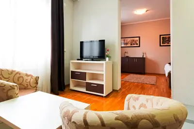 a living room with a tv and two chairs at Garni Hotel Nevski in Belgrade
