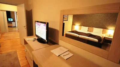 a hotel room with a bed and a desk with a television at Garni Hotel Nevski in Belgrade