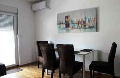 a dining room with a table and chairs and a painting at Apartment Leonis in Belgrade