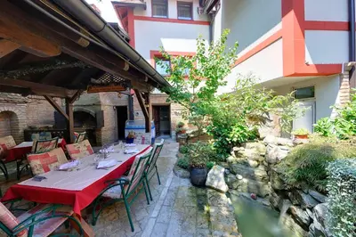 a restaurant with a table and chairs in a garden at Hotel Sucevic Garni in Belgrade