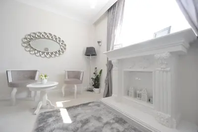 a white living room with a fireplace and a mirror at Margot Luxury Studio in Belgrade
