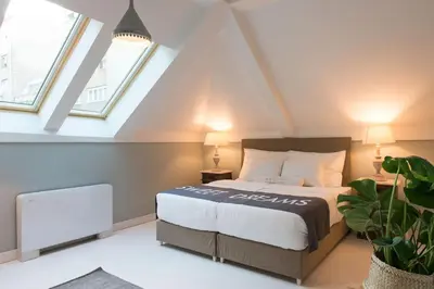 a attic bedroom with a bed and two windows at Smokvica Dorćol B&B in Belgrade