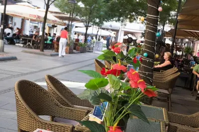 a table with chairs and flowers on a sidewalk at Double Decker Apartment in Belgrade