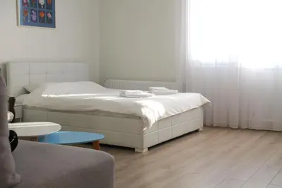 a bedroom with a bed with white sheets and a wooden floor at Rooftop Apartment Belgrade in Belgrade