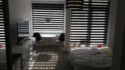 a bedroom with a bed and a table and windows at White City 1 Apartment in Belgrade