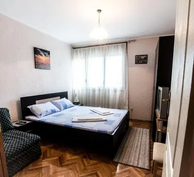 a bedroom with a bed and a chair and a window at Apartman Stankovic in Arandjelovac