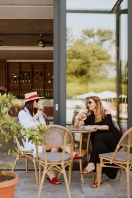 two women sitting at a table drinking wine at Hotel 1000 Ruza in Belgrade