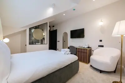 a hotel room with a large bed and a chair at Boem Exclusive Rooms Skadarlija in Belgrade