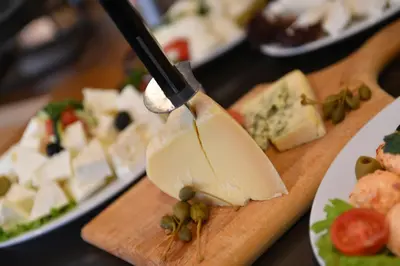 a cheese knife sticking into a block of cheese on a cutting board at Putnik Inn Belgrade in Belgrade
