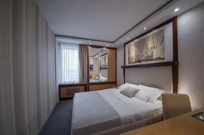 a bedroom with a bed and a table and a window at Putnik Inn Belgrade in Belgrade