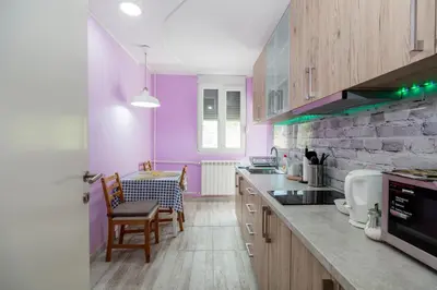 a kitchen with purple walls and wooden cabinets at Apartman Gloria 2 in Belgrade