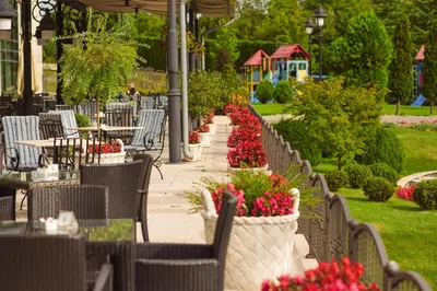 a patio with tables and chairs and flowers in flowerpots at A Hoteli - Hotel Izvor in Arandjelovac