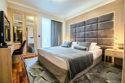 a bedroom with a large bed and a television at A Hoteli - Hotel Izvor in Arandjelovac