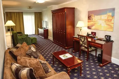 a living room with a couch and a desk in a hotel room at A Hoteli - Hotel Izvor in Arandjelovac