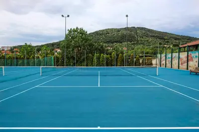 a tennis court with a mountain in the background at A Hoteli - Hotel Izvor in Arandjelovac