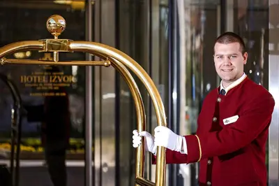 a man in red uniform holding a gold door at A Hoteli - Hotel Izvor in Arandjelovac