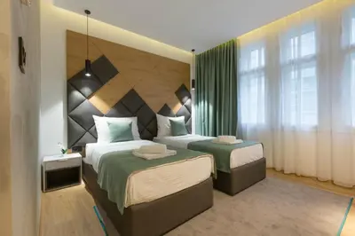 a bedroom with two beds and a large window at Capital Hotel Garni in Belgrade