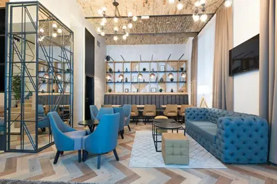 a lobby with a blue couch and tables and chairs at Capital Hotel Garni in Belgrade