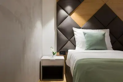 a bedroom with a bed with a wooden headboard at Capital Hotel Garni in Belgrade