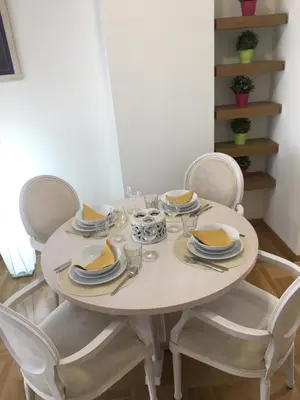 a white dining room table with chairs and plates and bowls at Apartment Posejdon in Belgrade