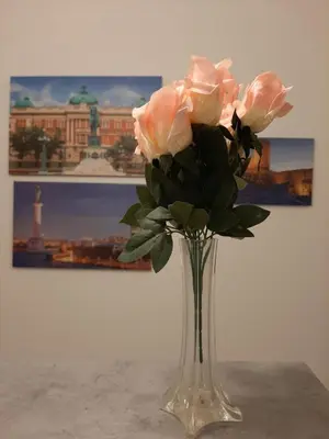 a glass vase with pink roses in front of a painting at Apartment Queen in Belgrade