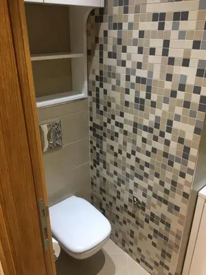 a bathroom with a toilet and a tiled wall at Apartment Triton in Belgrade