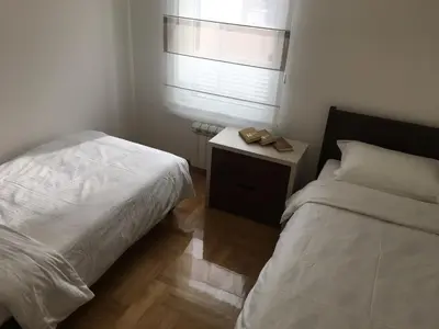 a bedroom with a bed and a nightstand and a window at Apartment Triton in Belgrade