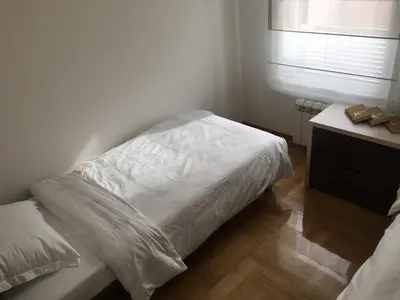 a bedroom with a white bed and a desk with a window at Apartment Triton in Belgrade