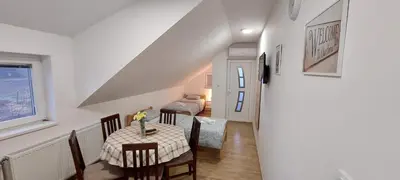 a dining room with a table and a room with a bed at ANA Apartment in Dobanovci