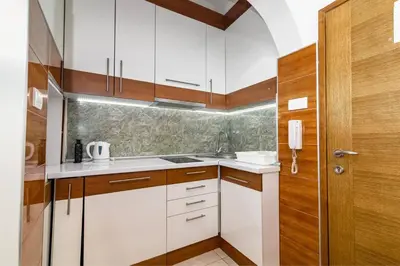 a kitchen with white cabinets and a wooden door at Marcel Apartments in Belgrade