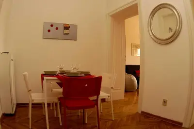 a dining room table with red chairs and a mirror at Bridge apartment in Belgrade