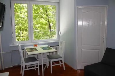 a small table and chairs in a room with a window at St. Sava Slavija Apartment in Belgrade
