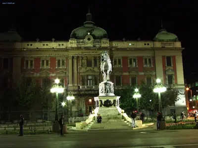 a statue in front of a large building at night at De Luxe Republic Square Apartment of 100sqm in Belgrade