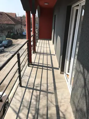 a balcony of a house with shadows on the ground at Five Apartments in Inđija
