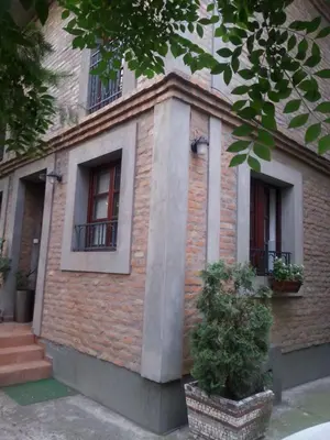 a brick building with two windows and a plant at Studio Hram in Belgrade