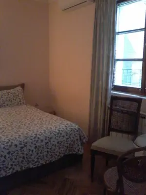 a bedroom with a bed and a chair and a window at Studio Hram in Belgrade