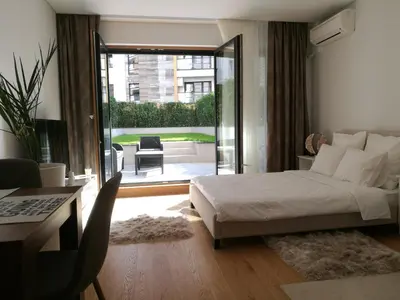 a bedroom with a bed and a view of a patio at Garden Apartment Sun City in Belgrade