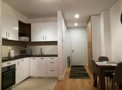 a kitchen with white cabinets and a dining table at Garden Apartment Sun City in Belgrade