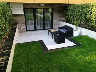 a patio with a chair and a table in the grass at Garden Apartment Sun City in Belgrade