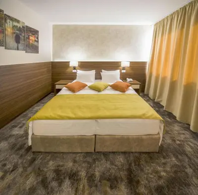 a bedroom with a large bed with yellow sheets and pillows at Hotel Marshal Garni in Belgrade