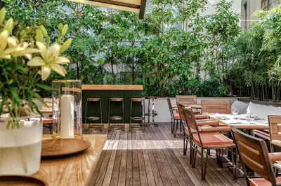 a restaurant with tables and chairs and plants at Square Nine Hotel Belgrade-The Leading Hotels of The World in Belgrade