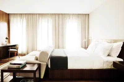 a bedroom with a large white bed and a table at Square Nine Hotel Belgrade-The Leading Hotels of The World in Belgrade
