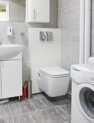 a bathroom with a toilet and a sink and a washing machine at Apartment La Bombonera in Belgrade