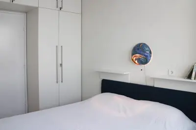 a bedroom with a white bed and a blue plate on the wall at Apartment La Bombonera in Belgrade