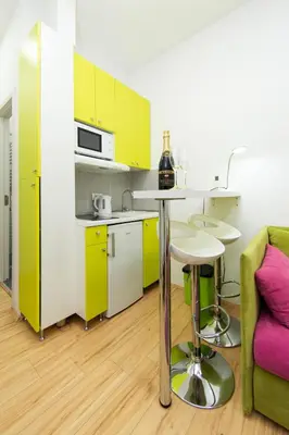 a kitchen with yellow cabinets and a table and a couch at Balkan-inn Apartment Terazije in Belgrade