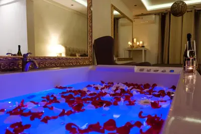 a table with red flowers on it with a mirror at Central Business Apartments Jacuzzi in Belgrade