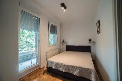 a small bedroom with a bed and a window at Arena East Apartment in Belgrade