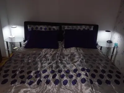 a bed with blue pillows in a bedroom with two tables at Apartment Aska in Belgrade